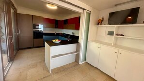 Een moderne keuken met een centraal eiland, witte kasten en een inbouwtelevisieplank.