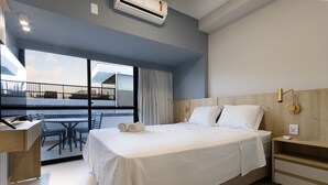 Una habitación de hotel moderna con una cama grande, un escritorio y un balcón con mobiliario exterior.