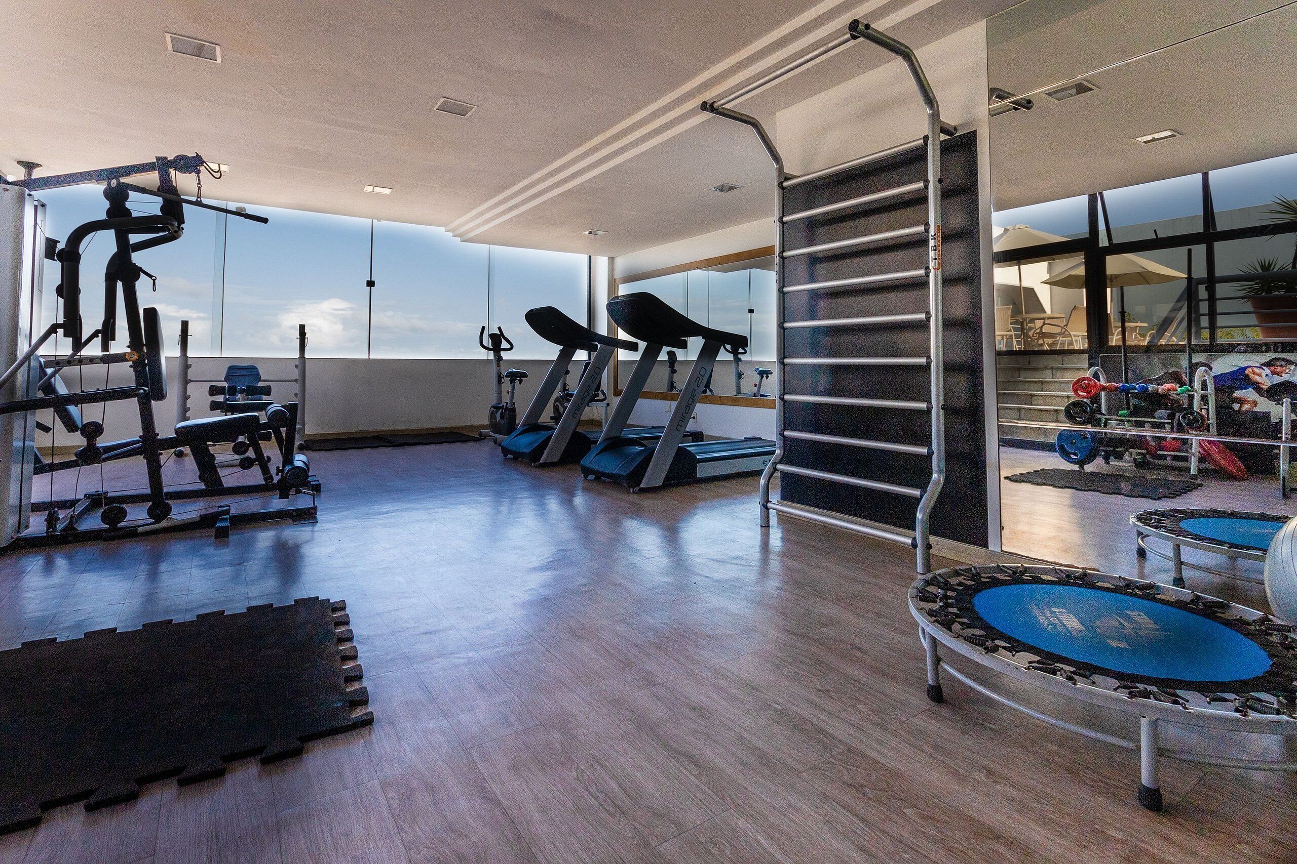 Un gimnasio con cintas de correr, máquinas de pesas y un espejo grande.