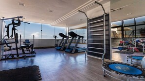 Un gimnasio con cintas de correr, máquinas de pesas y un espejo grande.