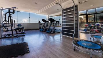 Un gimnasio con cintas de correr, máquinas de pesas y un espejo grande.