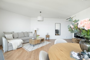 A modern living room with a sofa, coffee table, and dining table.