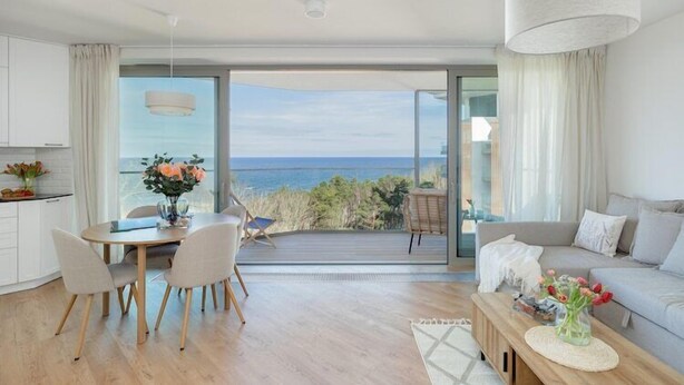 A modern living room with a large sliding glass door leading to a balcony with a view of the sea. - Stunning Seaview Retreat for 4 in Pobierowo (Pobierowo)