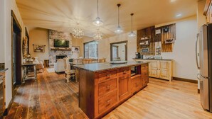 Un'ampia cucina con una grande isola, mobili in legno e illuminazione a sospensione.