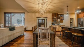Un'ampia cucina con un tavolo da pranzo in legno, sgabelli da bar e una grande finestra con vista su un paesaggio innevato.
