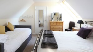 Een slaapkamer met een bed, een dressoir, een spiegel, een nachtkastje en een raam.