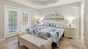 Un dormitorio con cama, mesitas de noche, un banco y un ventilador de techo.