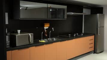 Cozinha moderna com micro-ondas, pia e geladeira de aço inoxidável.