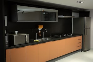 A modern kitchen with a microwave, sink, and stainless steel refrigerator. - Urban #105 - Quadruple in Tambau by Carpediem (João Pessoa)
