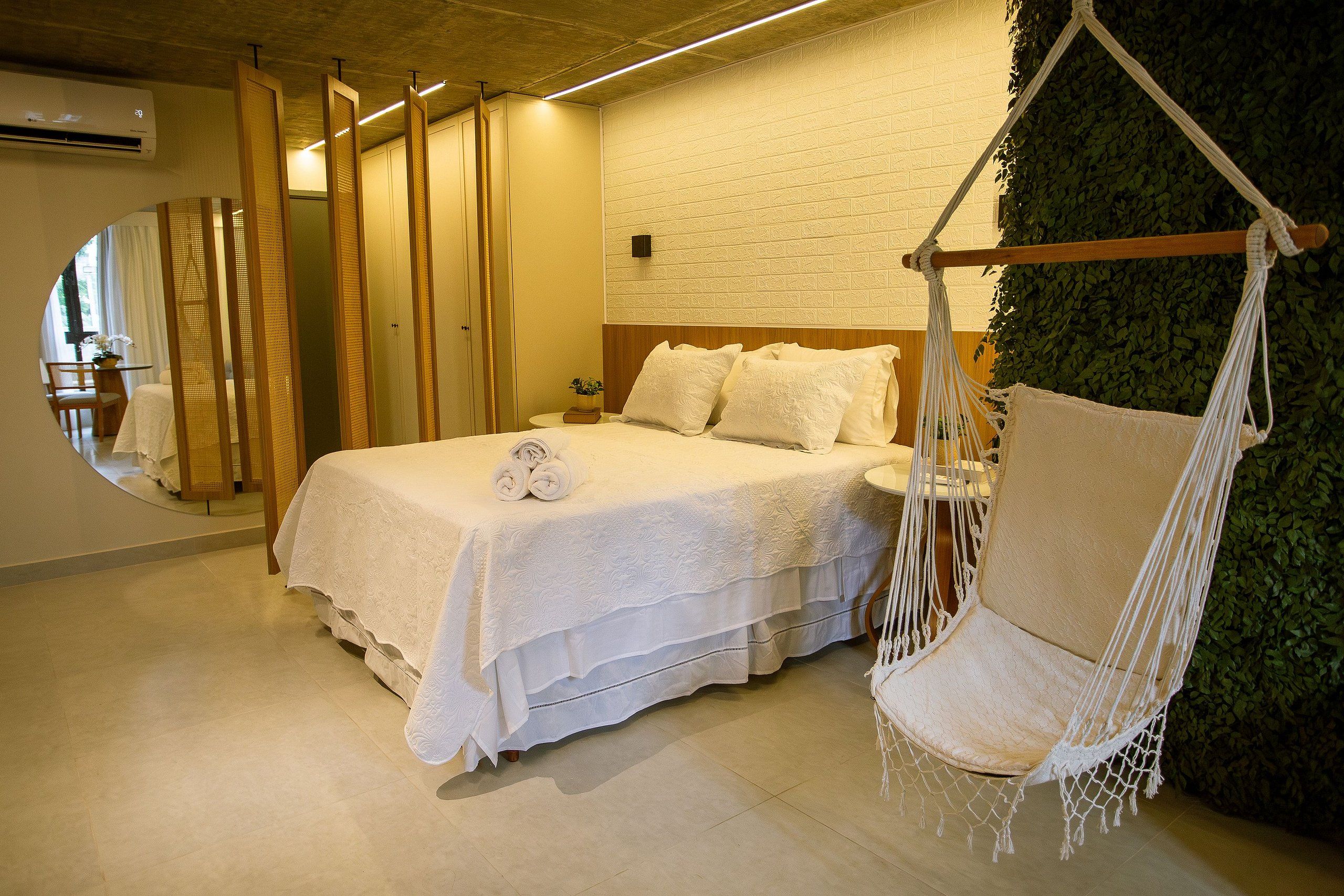 A bedroom with a bed, a hanging chair, and a green wall.