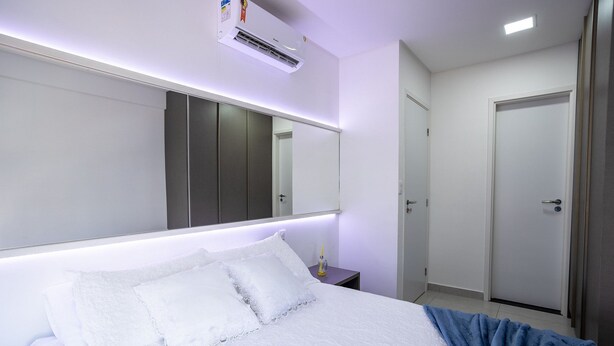 Quarto de hotel com cama grande, mesa de cabeceira, espelho, ar condicionado e porta.