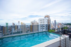 Une piscine sur le toit, offrant une vue sur la ville et entourée d’immeubles.