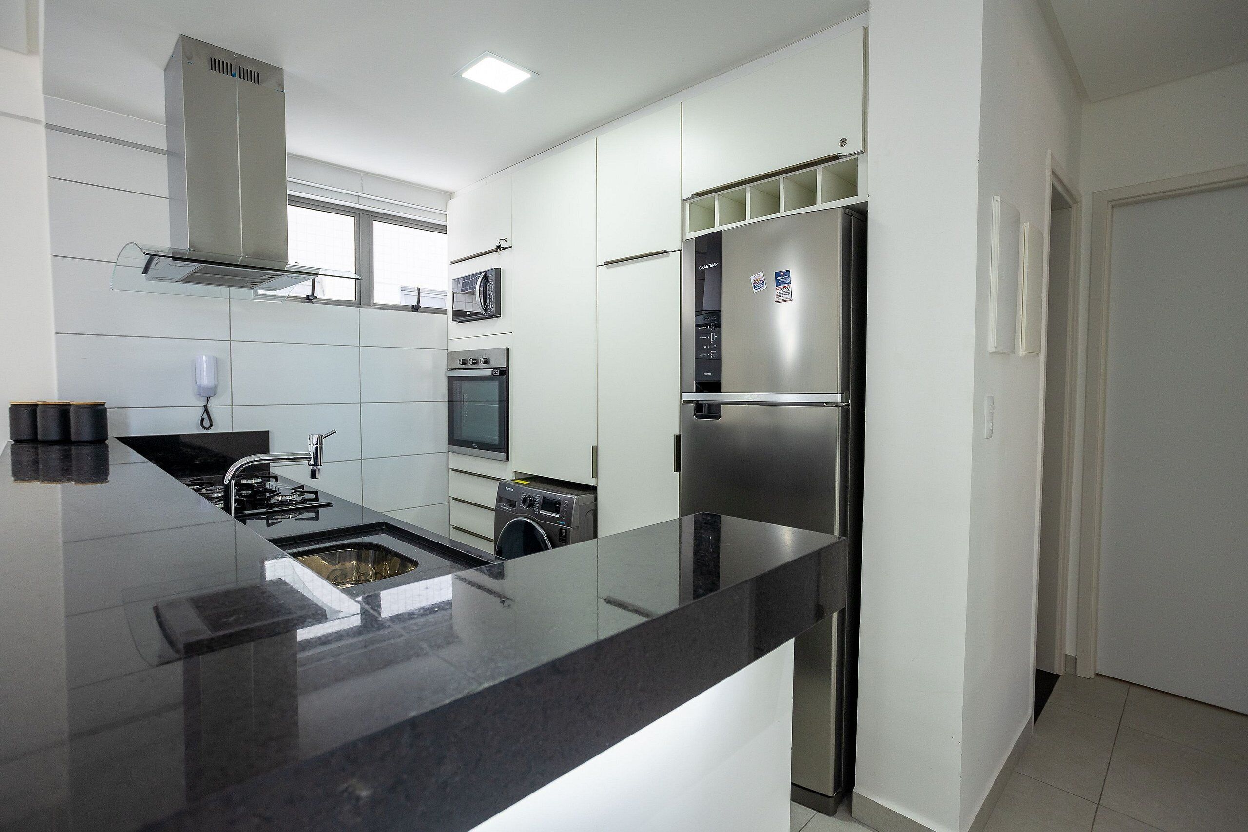 A modern kitchen with a stainless steel refrigerator, microwave, oven, and a built-in washing machine.