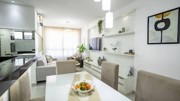 Ein modernes Wohnzimmer mit Esstisch, Sofa und Fernseher.