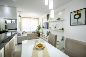 Un salon moderne avec une table à manger, un canapé et un téléviseur.