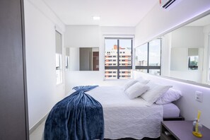 Une chambre d’hôtel moderne avec un grand lit, une table de chevet, un miroir et une vue sur le paysage urbain.