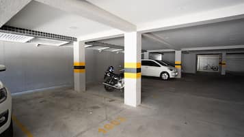 Un parking avec des planchers en béton, des piliers blancs et des bandes jaunes.