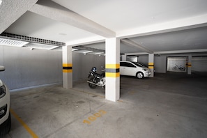 A parking garage with concrete floors, white pillars, and yellow stripes. - Tropical Hub #1002 - Apartment in Manaira by Carpediem (João Pessoa)