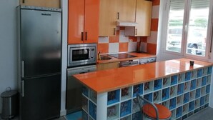 Cozinha equipada com geladeira, forno, micro-ondas e pia.