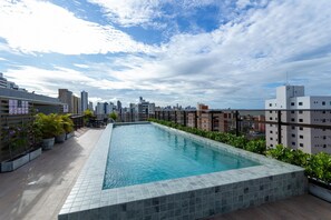 A rooftop swimming pool with a cityscape view, surrounded by potted plants and a tiled deck. - W Gratitude #1006 - Apartment in Manaira by Carpediem (João Pessoa)