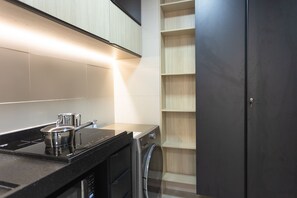 Eine Küche mit Herd, Spüle und Geschirrspüler. Es gibt einen Holzschrank mit offenen Regalen.