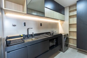 A modern kitchen with a built-in oven, microwave, and dishwasher, wooden shelves, and a black countertop. - W Gratitude #1006 - Apartment in Manaira by Carpediem (João Pessoa)