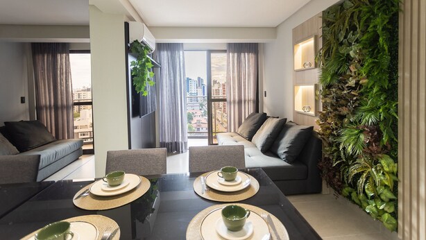 Un soggiorno moderno con zona pranzo, divano e parete decorata con elementi verdi.