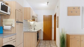 Eine kompakte Küche mit Holzschränken, einer Mikrowelle, einem Spülbecken und einem Blumentopf.