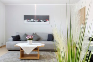 A modern living room with a grey sofa, a coffee table, and a painting on the wall.