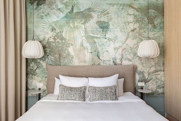 Quarto com cama grande, duas mesas de cabeceira e cabeceira com painel de parede texturizado.