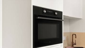 A modern kitchen with a built-in oven, a stainless steel faucet, and a black countertop.