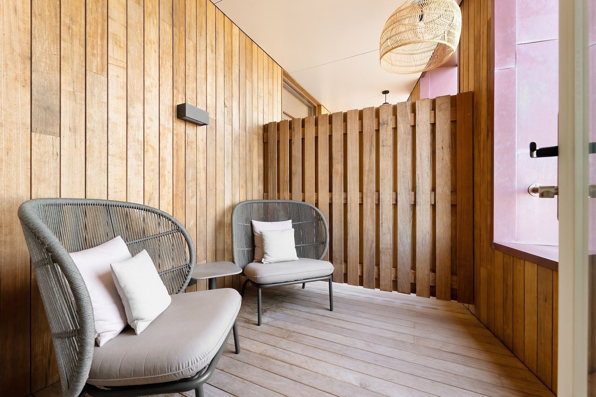 A wooden-paneled room with two wicker chairs and a small table.