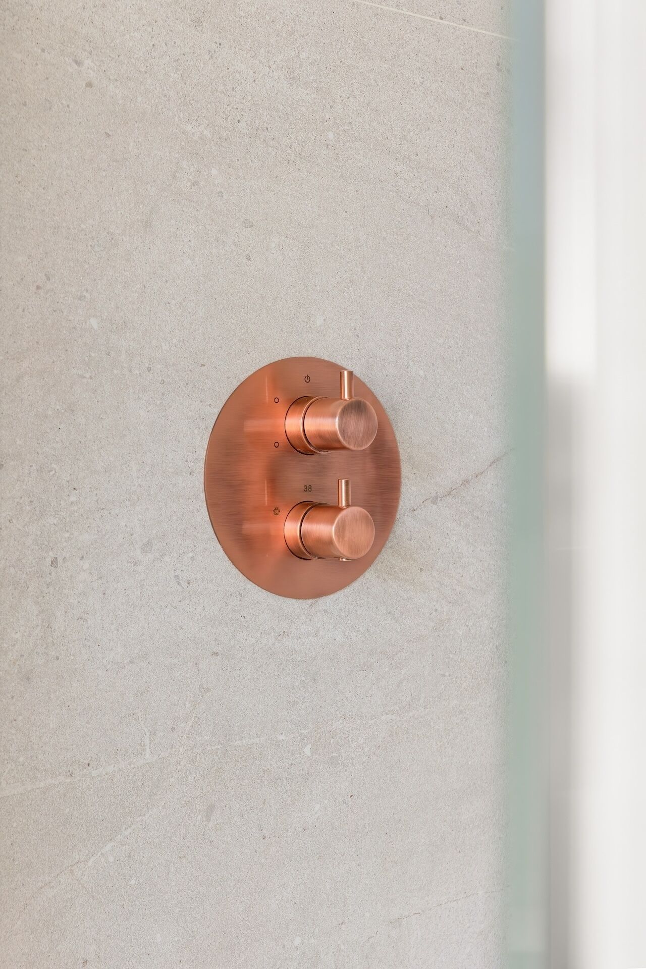 A copper faucet with two handles on a light-colored countertop.