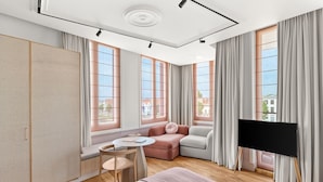 A modern hotel room with a large window, a flat-screen TV, a sofa, a small table, and a bed. - Hotel Copper (Middelburg)
