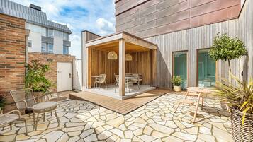 A patio area with stone flooring, outdoor furniture, and a wooden pergola.