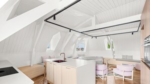 A modern loft-style apartment with an open-plan kitchen and living area, featuring a large island, wooden flooring, and white walls. - Hotel Copper (Middelburg)