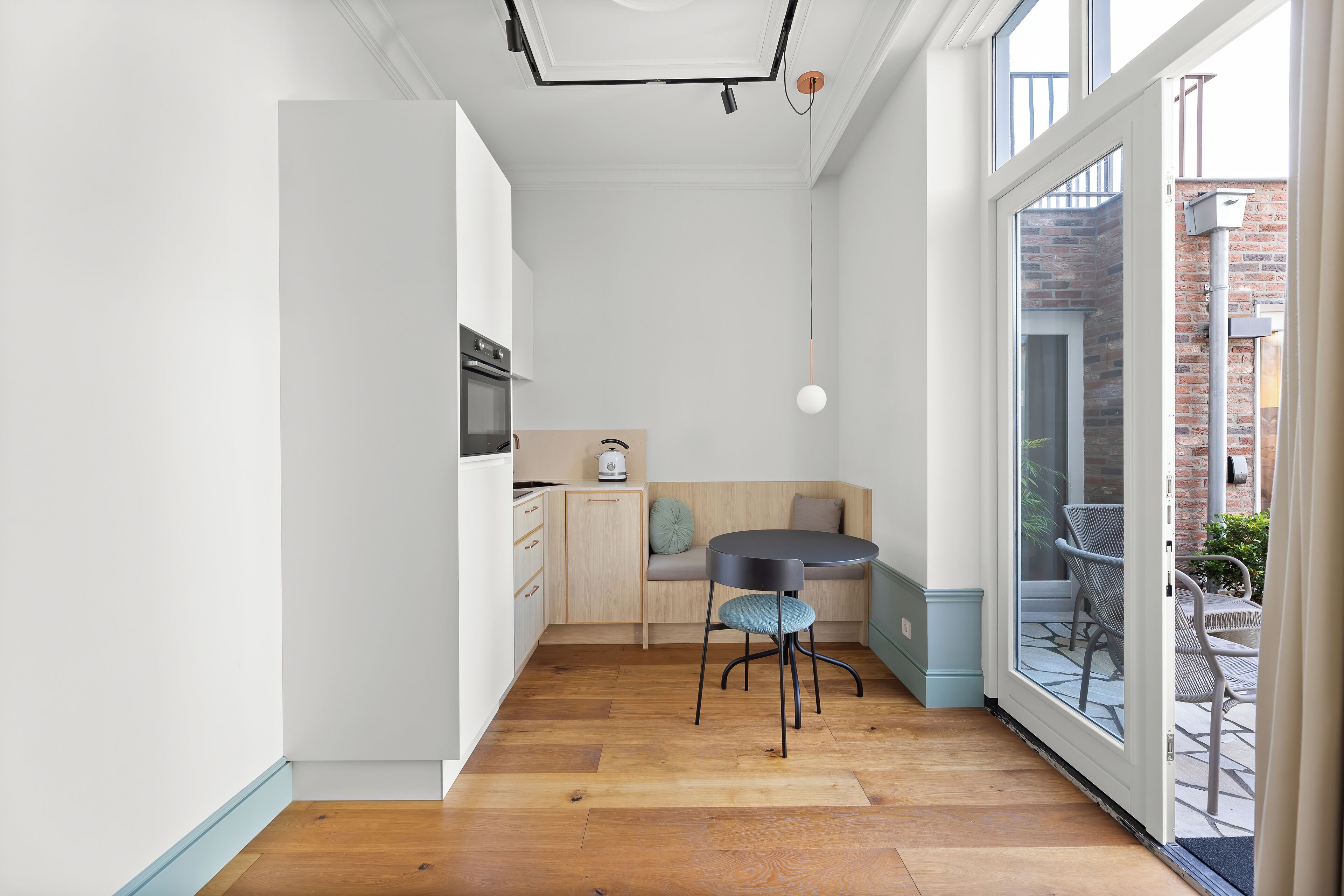 Una cocina moderna con comedor, suelo de madera y puerta de vidrio corrediza que da a un patio exterior.