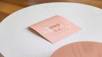 Una mesa pequeña y redonda, de color blanco, con un folleto rosa encima.