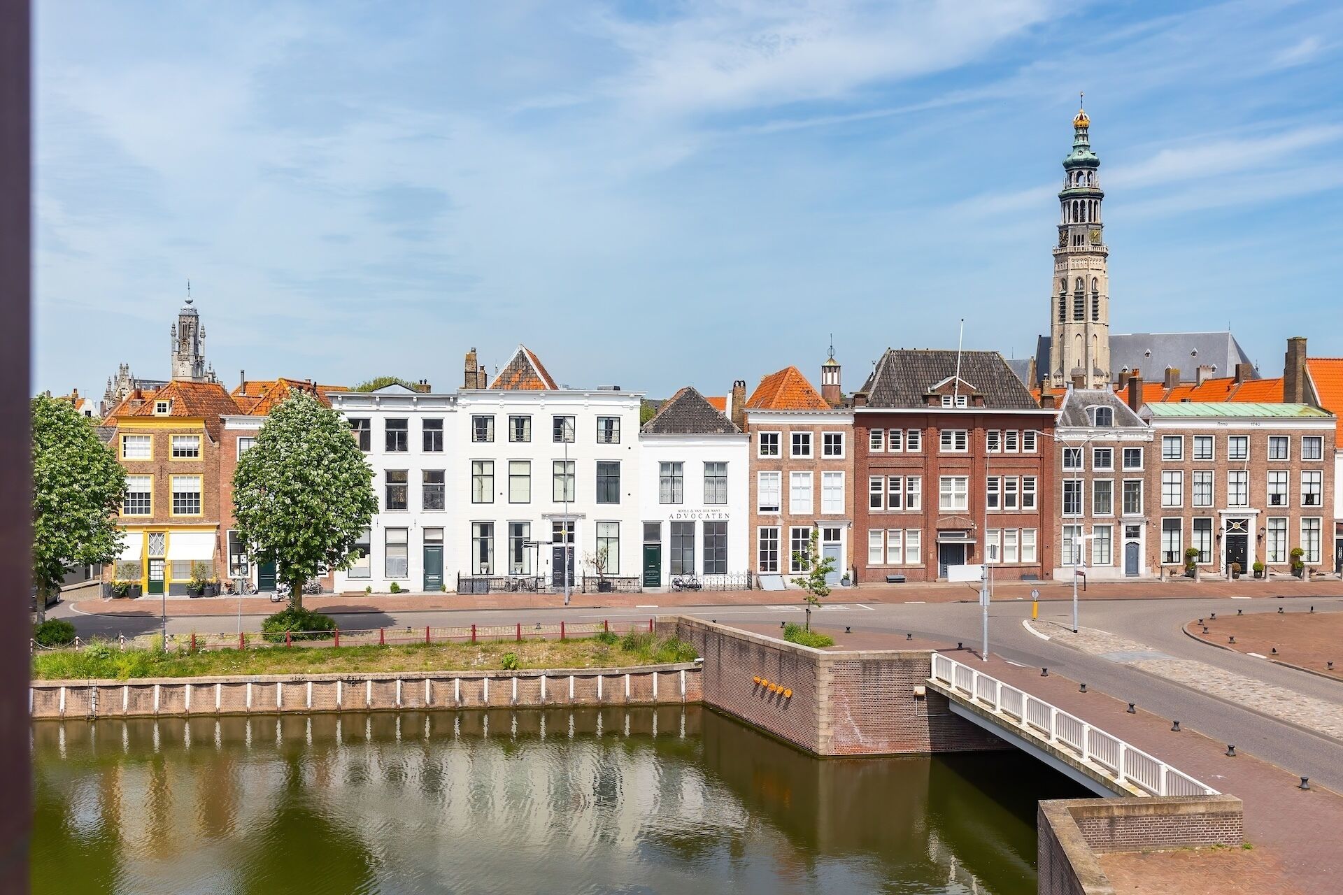 A canal with a bridge, historic buildings, and a prominent tower.