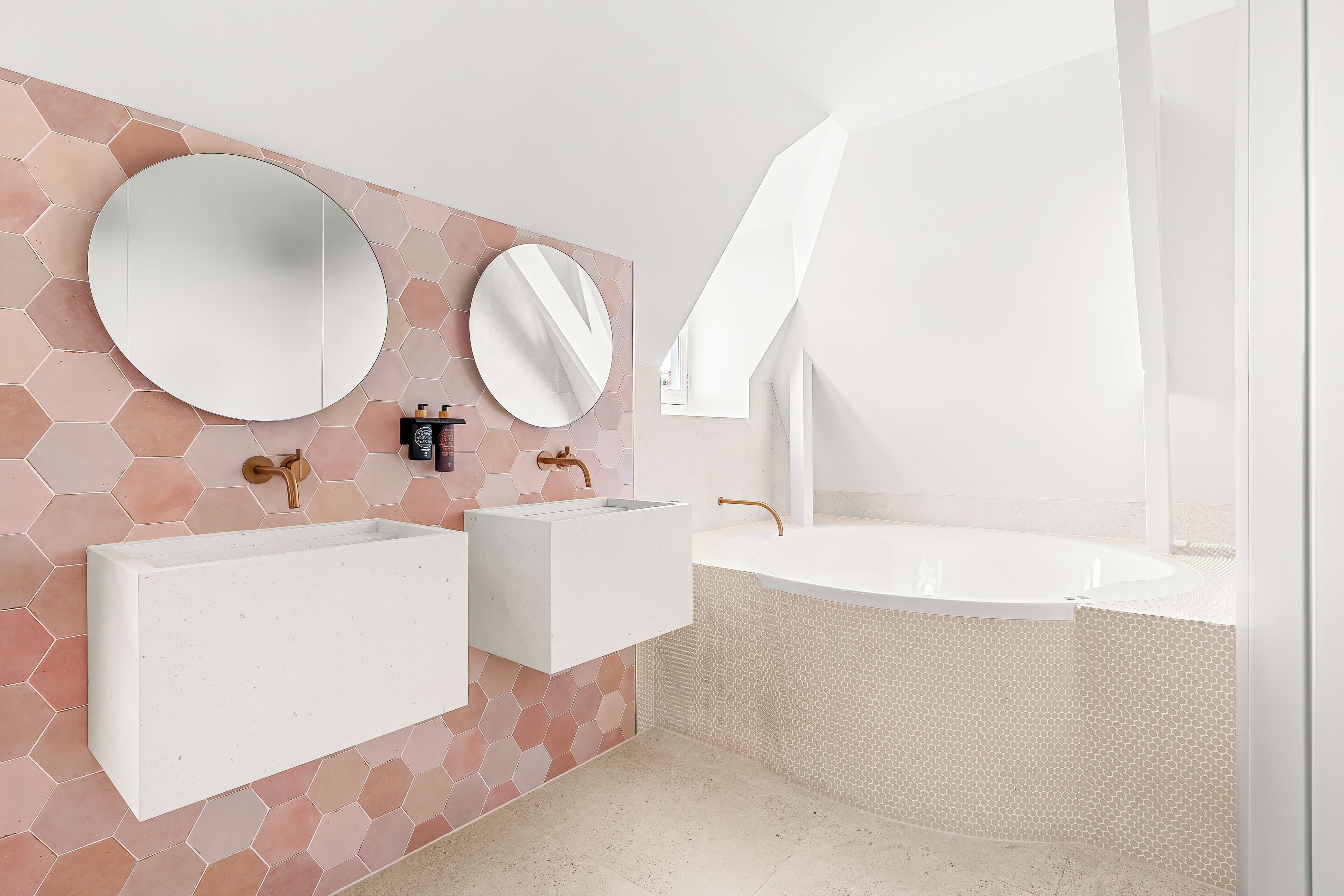 A modern bathroom with a large rectangular sink, a round mirror, and a freestanding bathtub.