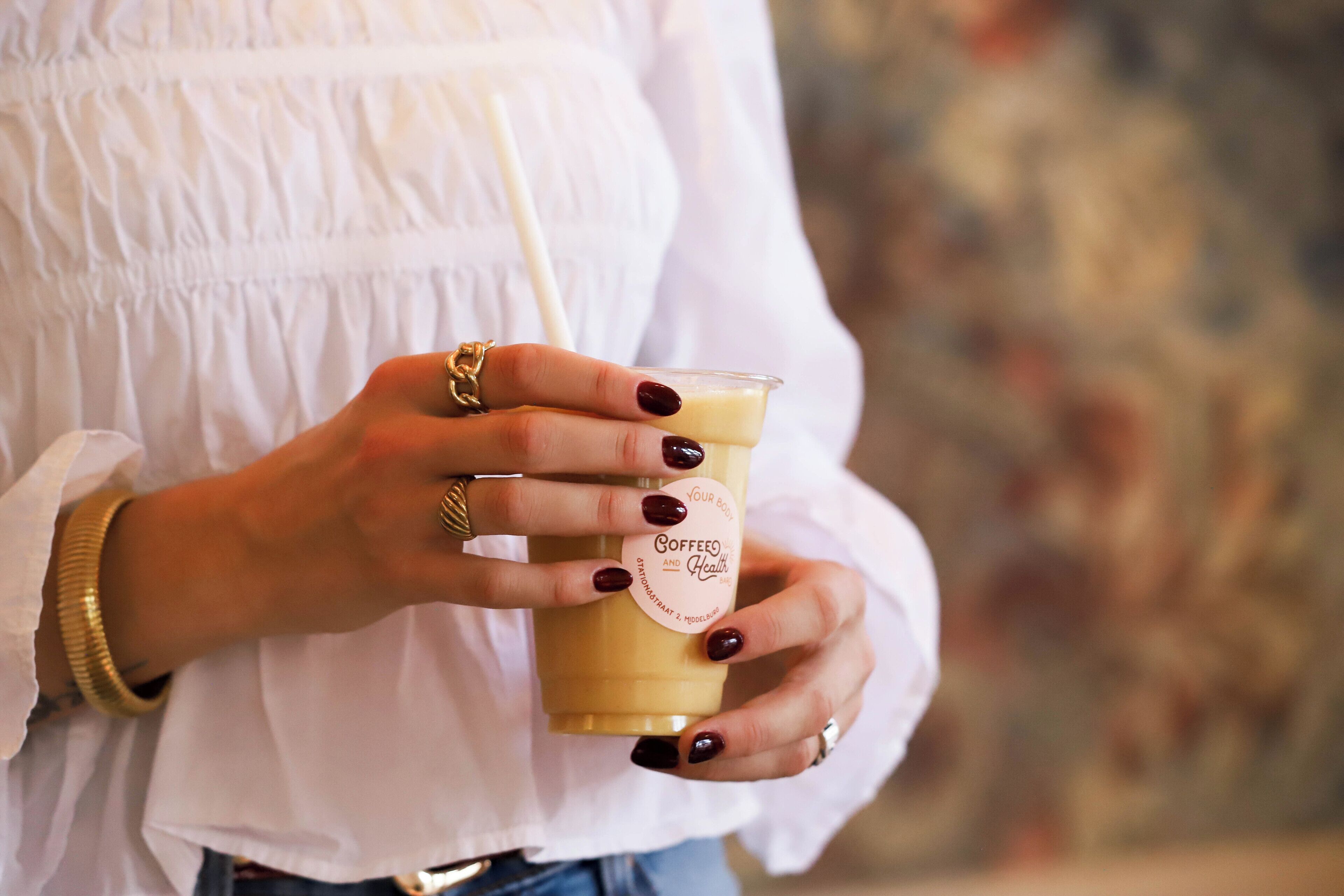 Une personne tenant une tasse sur laquelle est apposée une étiquette indiquant : « Votre café, votre corps, votre santé. »