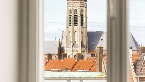 A view of a historic tower with a clock, through a window with a white frame. - Hotel Copper (Middelburg)