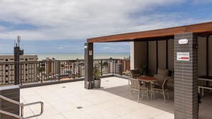 A rooftop terrace with a view of the sea, a table with chairs, and a sign indicating a smoking area. - Mindset #207 - Comfort and Location by Carpediem (João Pessoa)