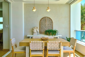 A dining area with a wooden table, woven chairs, and pendant lighting. - ®{Marbella~LUX~Sunsets} Beachfront+Pool+Families (Playa Juan Dolio)