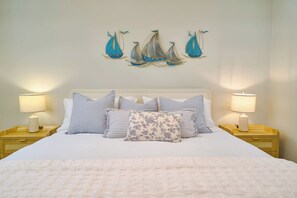 A neatly made bed with a white duvet and multiple pillows, flanked by two bedside tables with lamps, in a room with a simple, clean design. - ®{Marbella~LUX~Sunsets} Beachfront+Pool+Families (Playa Juan Dolio)