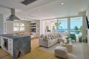 Um espaço de estar moderno com cozinha, sala de jantar e uma grande janela com vista para o oceano.