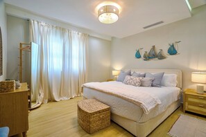 Quarto com cama, mesas de cabeceira, espelho, cômoda, cesta de vime e janela com cortinas.