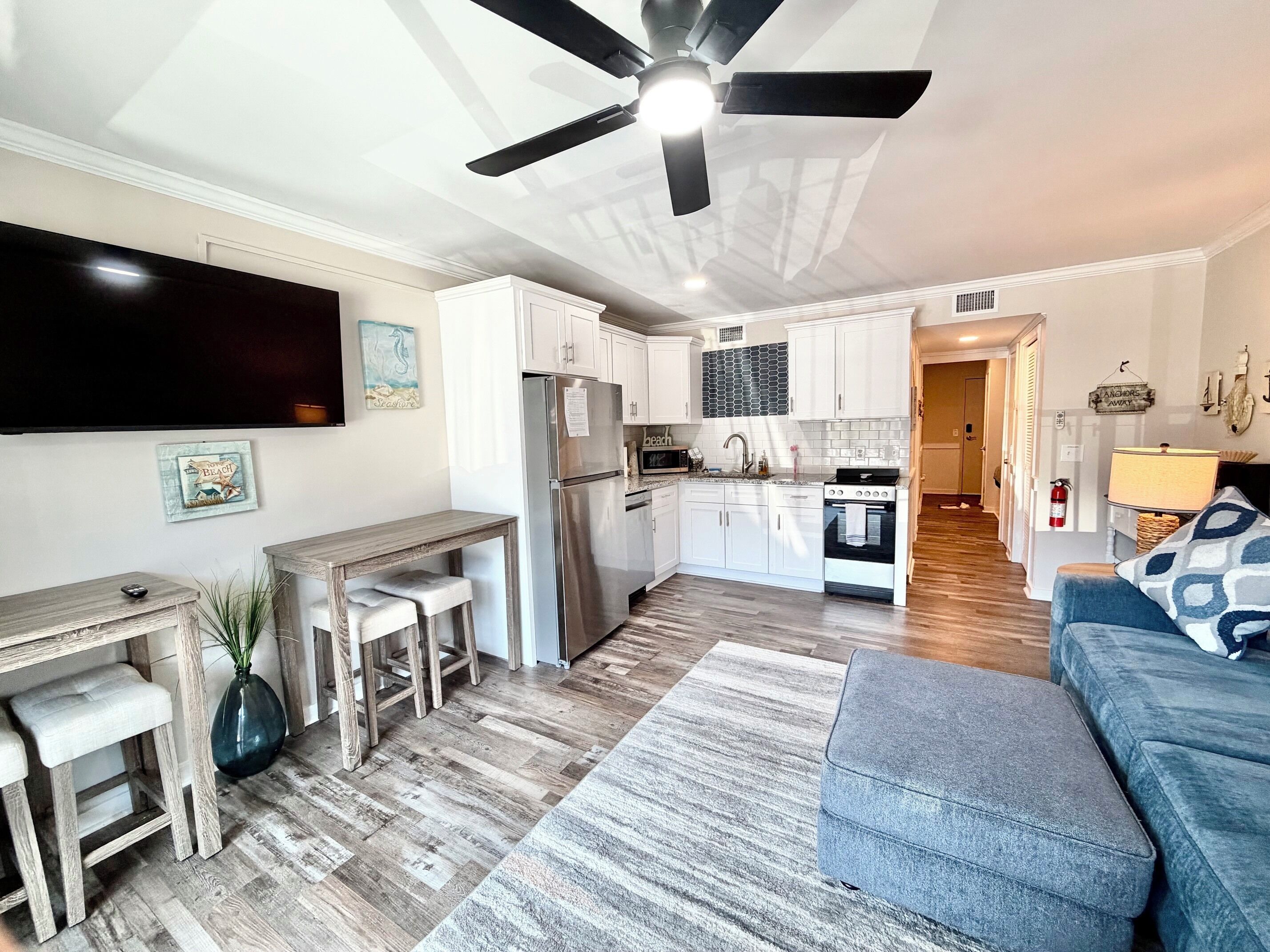A modern kitchen with white cabinets, a stainless steel refrigerator, and a built-in oven.