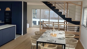 Ein modernes Interieur mit Essbereich, Küche und Treppe.