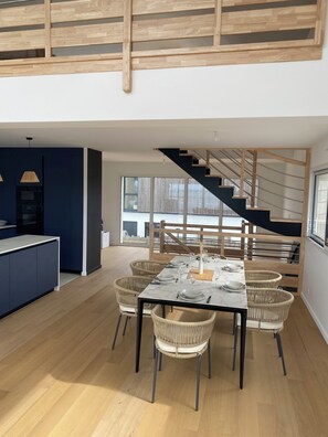 Un intérieur moderne comprenant un coin repas, une cuisine et un escalier.